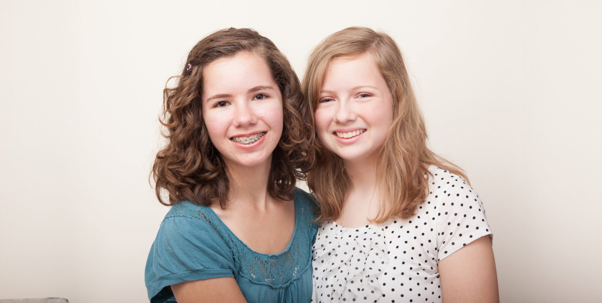 Young girl with braces smiling and hugging her friend