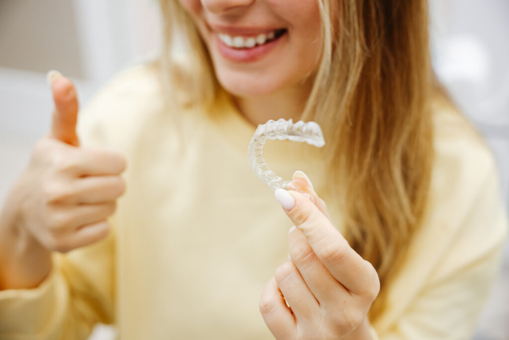 Dental Invisible Braces Or Silicone Trainer In The Hands Of A Young Smiling Women. Orthodontic Concept Invisalign