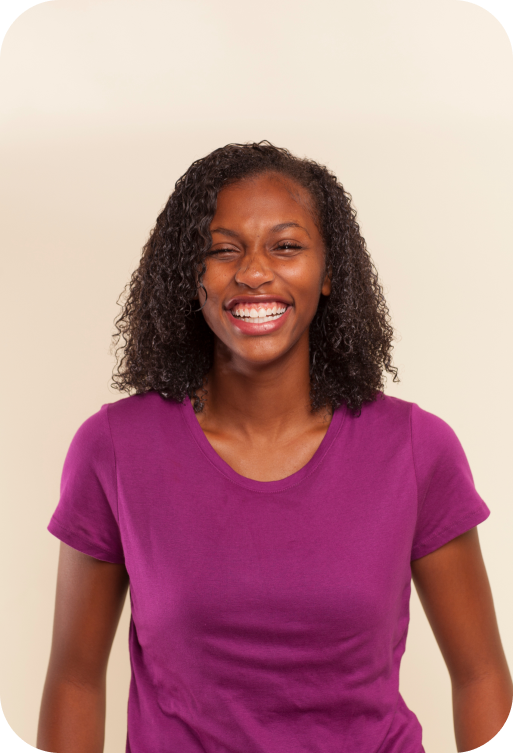 Young Woman With Beautiful Curly Hair Smiling In A Plum Shirt After Receiving Orthodontic Treatment