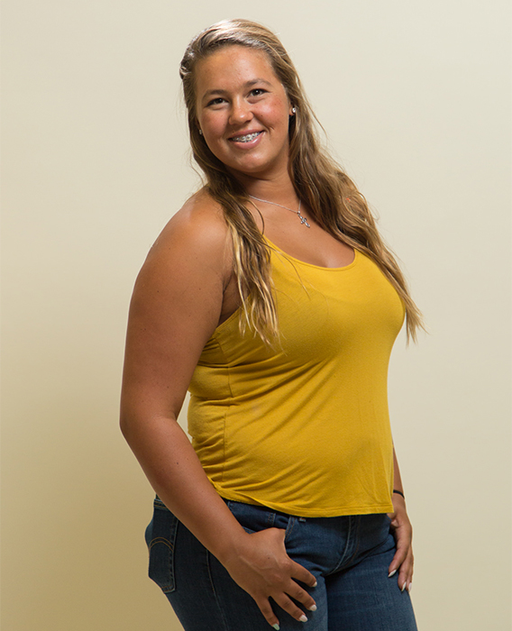 Teen with braces smiling and posing in a yellow tank top and jeans