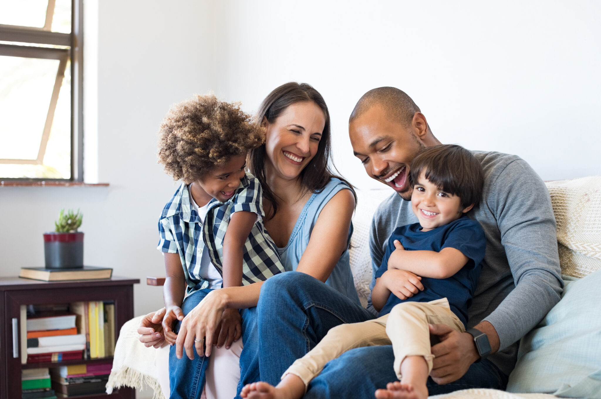 Smiling parents sitting with their two young children at home.