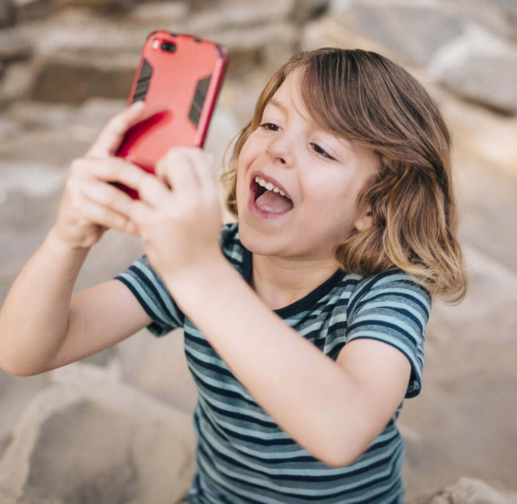 Kid Using A Mobile Phone And Smiling