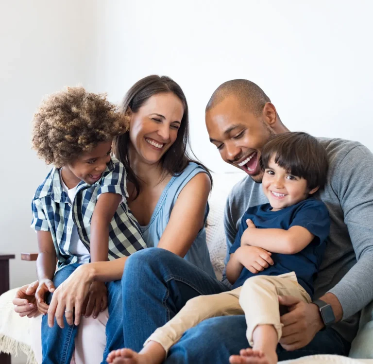 Smiling parents sitting with their two young children at home.